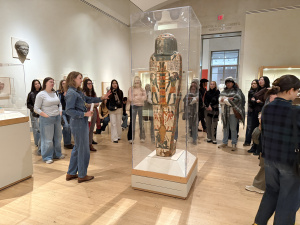 The group stands in a museum looking at a large sculpture. 