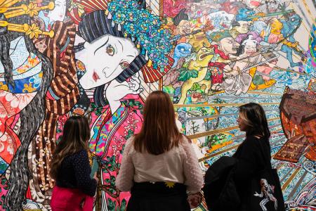 Three students look up at the artwork at a museum.