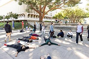 dancers laying on ground in front of Langson Library on UCI campus