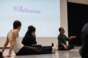 Dancer George Casel and two other dancers seated on floor in front of screen with word whiteness