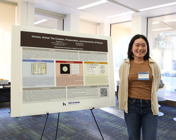 Smiling student standing in front of project poster board at the UFDH showcase in Langston Library 