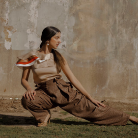 Girl wearing all brown clothes posing in front of a brown background