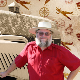 Mark Hall-Patton smiling and leaning against a metal vehicle with his hand