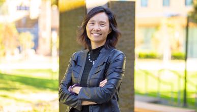 Judy Wu stands smiling in a bright, outdoor setting