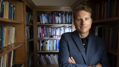 Duncan Pritchard poses with his arms crossed inside a library