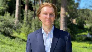 Image of man in suit with a green, nature background