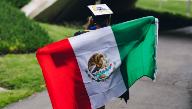 Chelsea Salinas holding a Mexican flag across her back as she walks away from the camera.