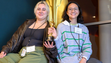 Olivia Clark sitting on a statue of an Emmy award