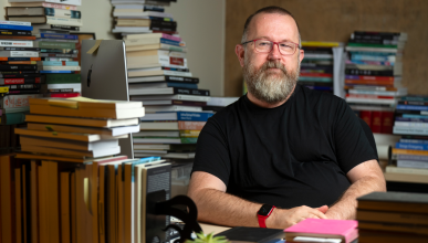 A photo of Jonathan sitting at his desk surrounded by books.