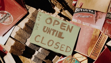 Open Until Closed sign sitting on a pile of bricks and books