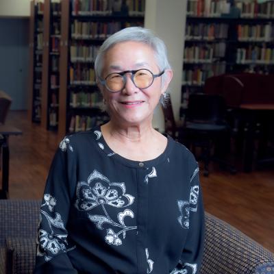 former UCI research librarian Christina Woo sitting in a library